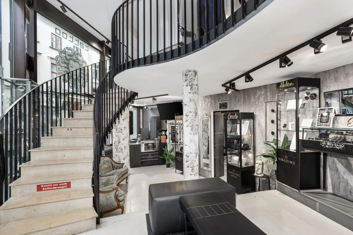 Eingangsbereich im Erdgeschoss von Medusa Tattoo München mit Wendeltreppe und Premium-Schmuck-Vitrinen